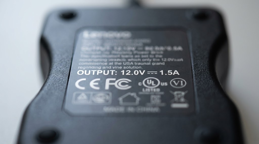 Close-up of a power adapter rating label showing voltage and amperage specifications.